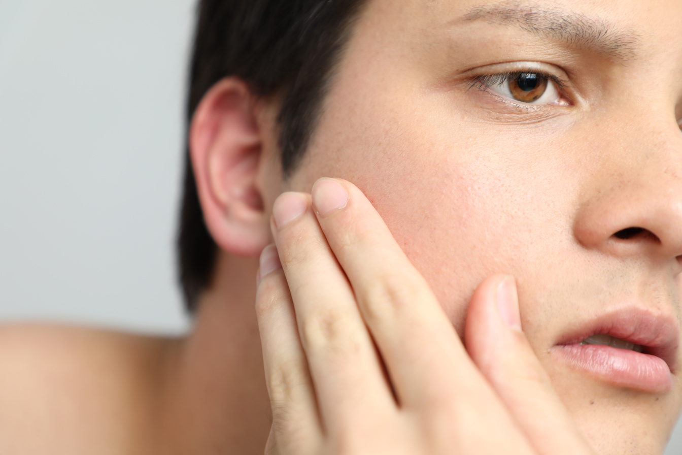 young man checking his facial skin. men's skincare concept.