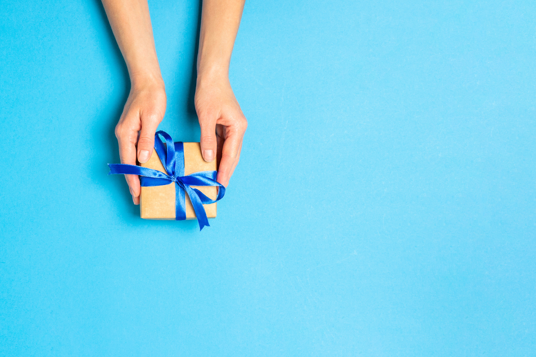Female hand holds, takes, get a gift on a blue background. Concept gift, wedding, valnetina day. Flat lay, top view